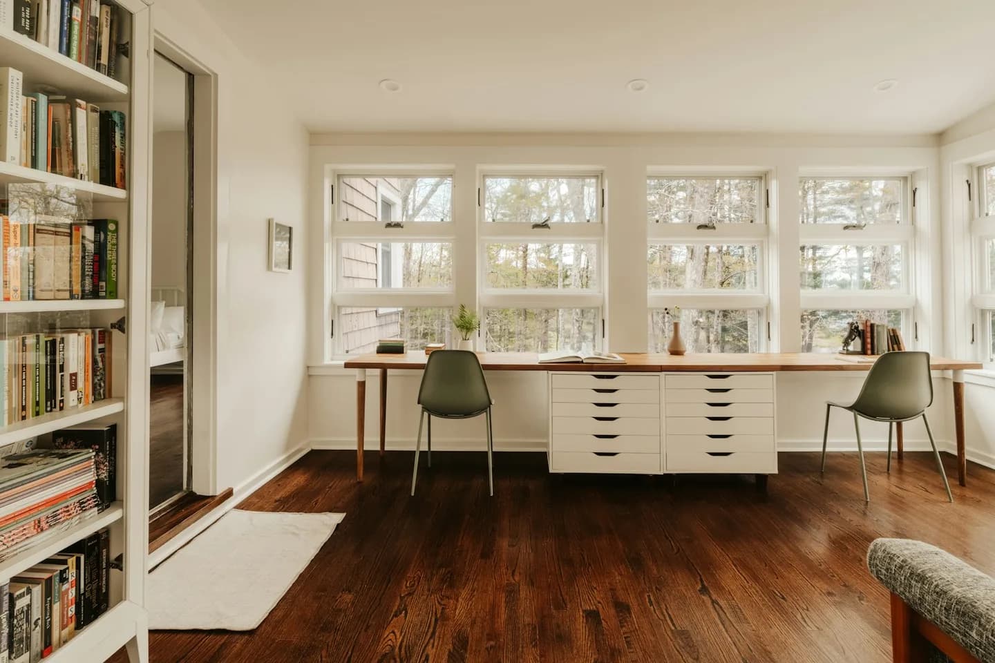 Illustrative home study with bookshelves, two desks and natural light
